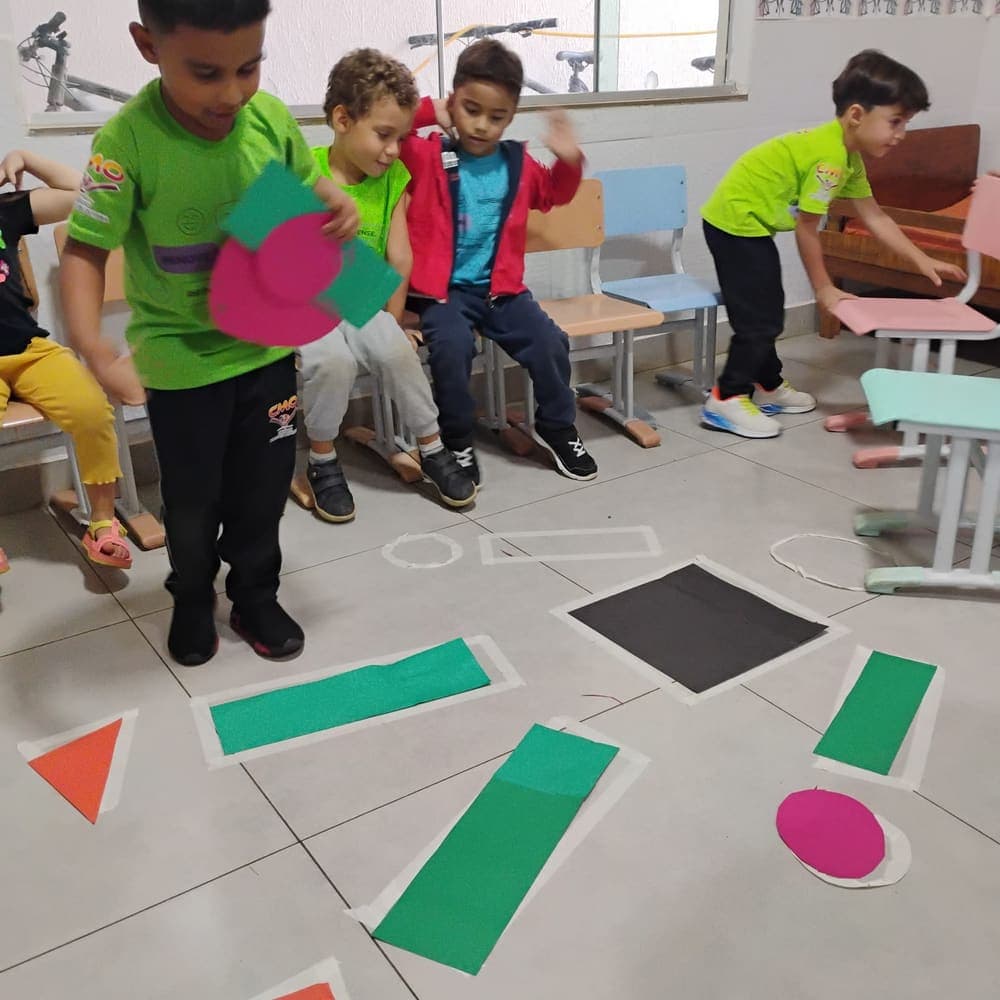 Crianças brincando com formas geométricas coloridas no chão da sala
